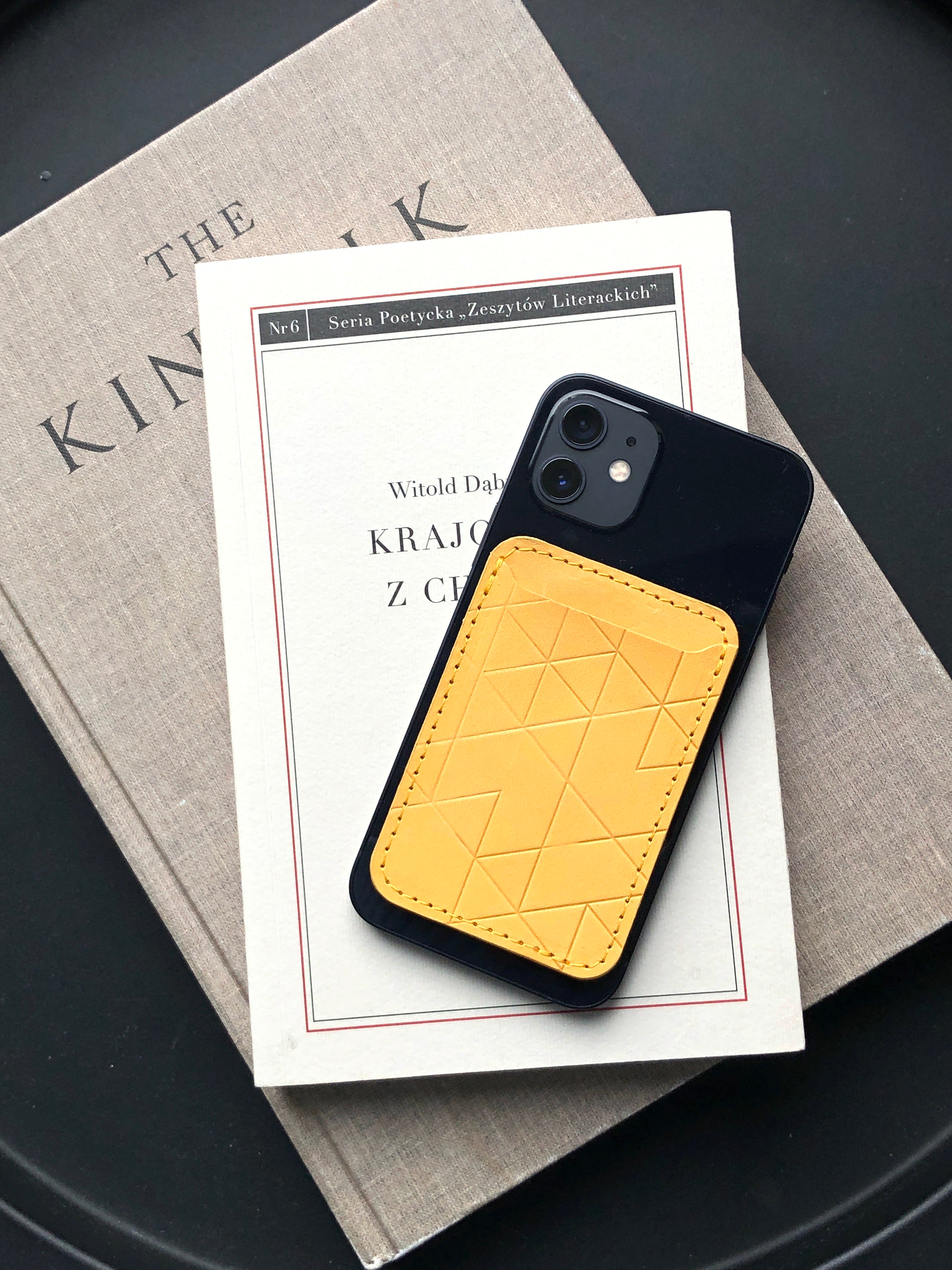 iPhonewith a yellow leather magsafe card wallet resting on top of books