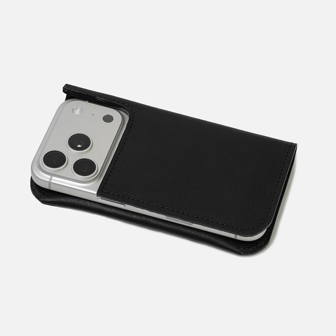 Black leather folio wallet holding a smartphone without a case, rear camera exposed, shown in a slim folded profile on a white background