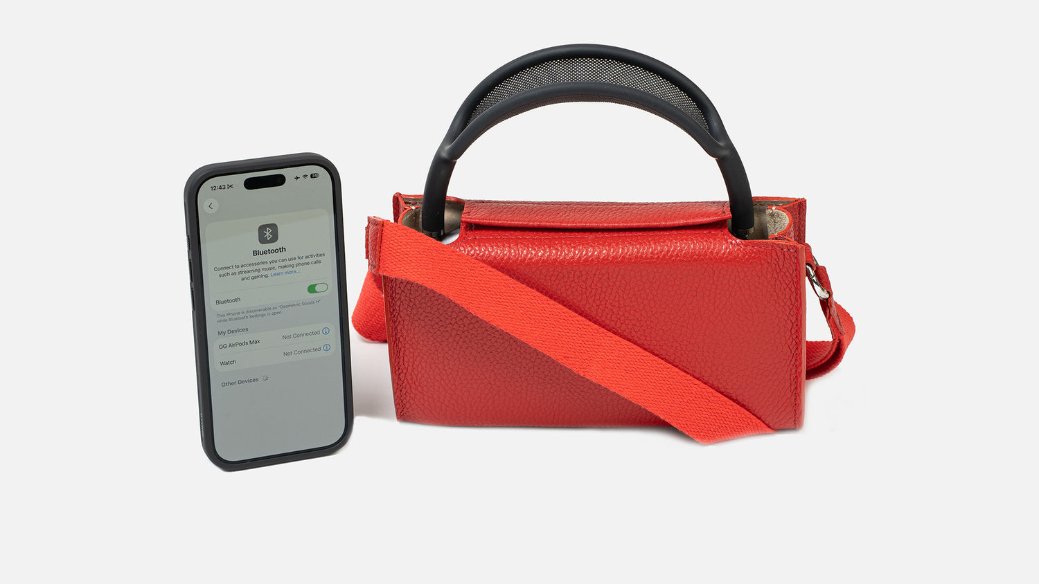 Red leather AirPods Max case bag with webbing strap and top handle, shown next to an iPhone on the Bluetooth settings screen.