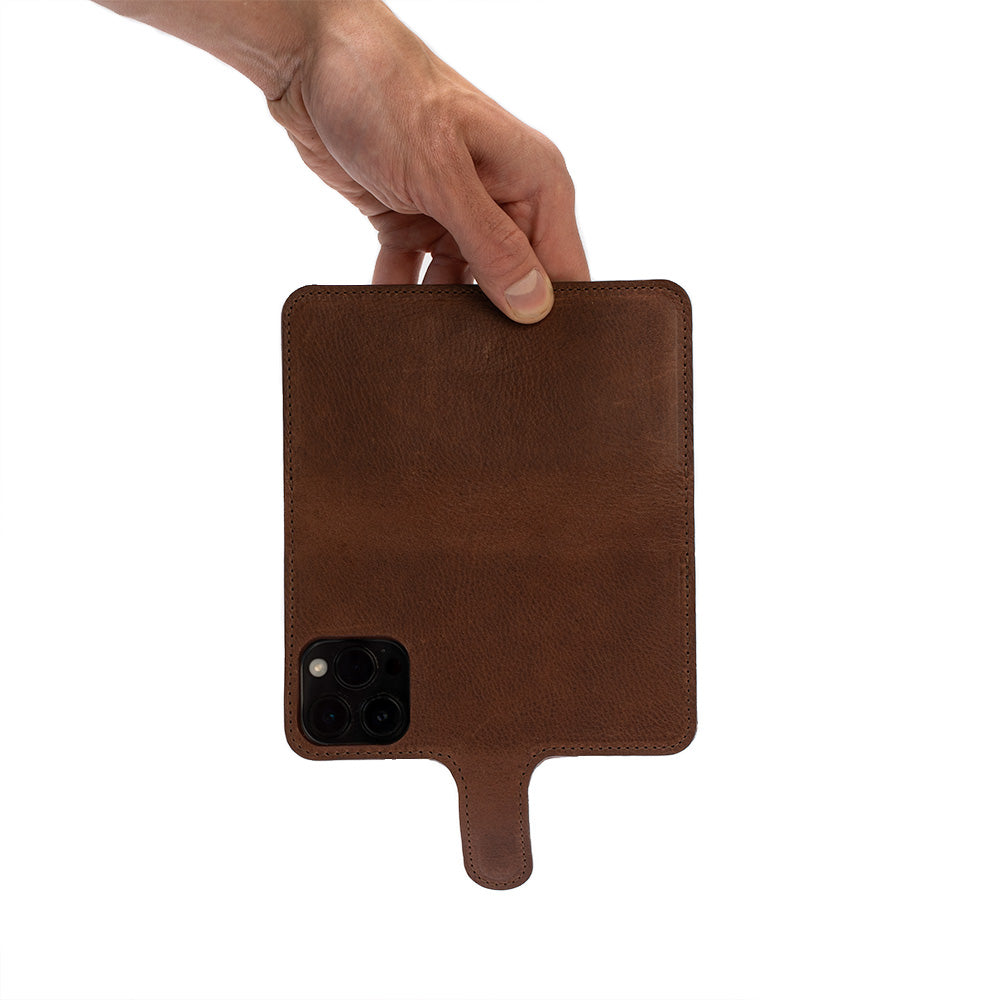 Hand holding a brown leather MagSafe-compatible folio case with strong magnet