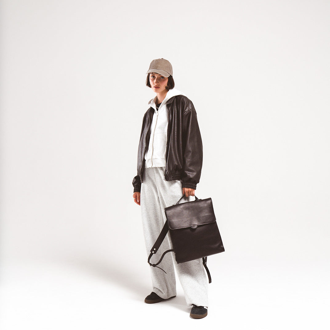 Leather backpack for woman showcased by a stylish young woman in a leather jacket and casual grey attire, emphasizing its versatile design