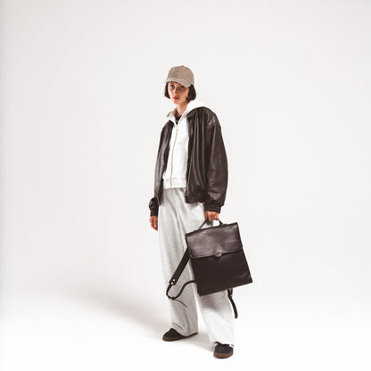 Leather backpack for woman showcased by a stylish young woman in a leather jacket and casual grey attire, emphasizing its versatile design