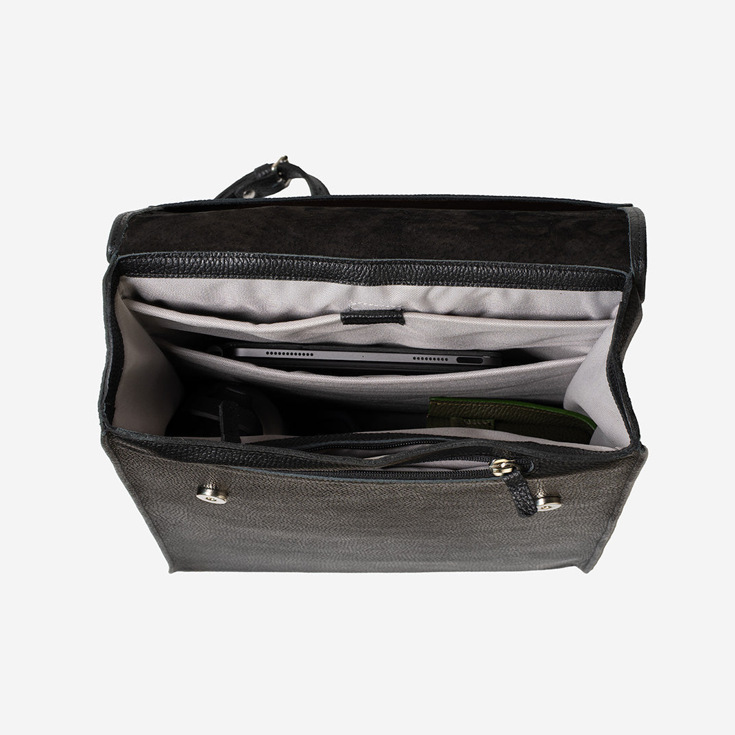 Interior of big leather rucksack with padded laptop and tablet compartments, waterproof lining, and zipper pocket