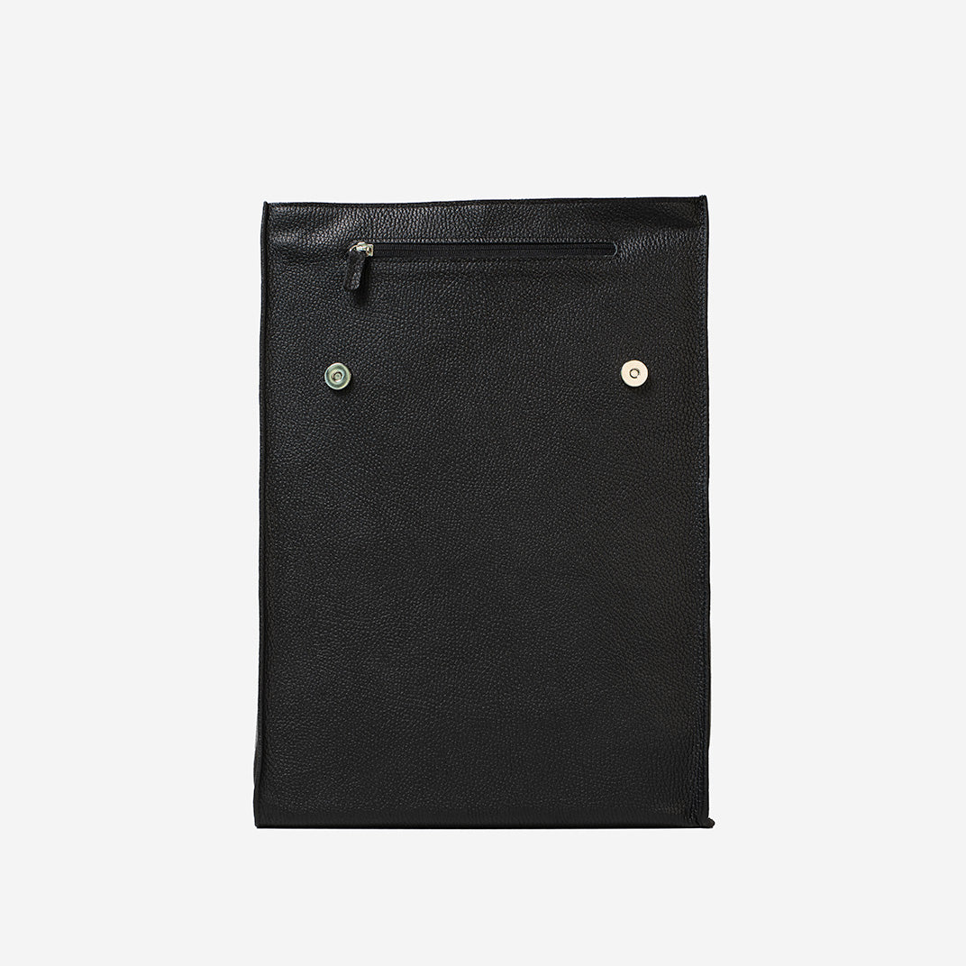 Front view of black leather daypack with magnetic closure and exterior zipper pocket under flap