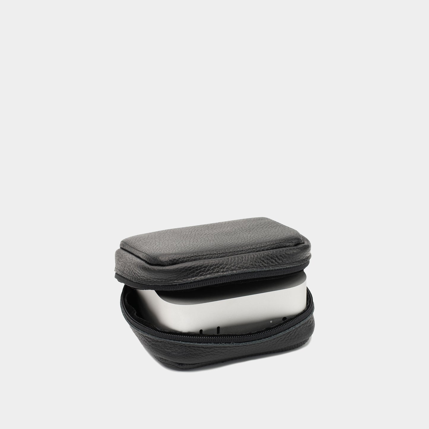 Angled black leather Mac Mini case showing the zip opening and device seated inside