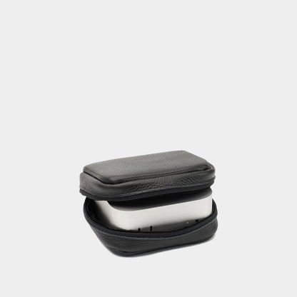 Angled black leather Mac Mini case showing the zip opening and device seated inside