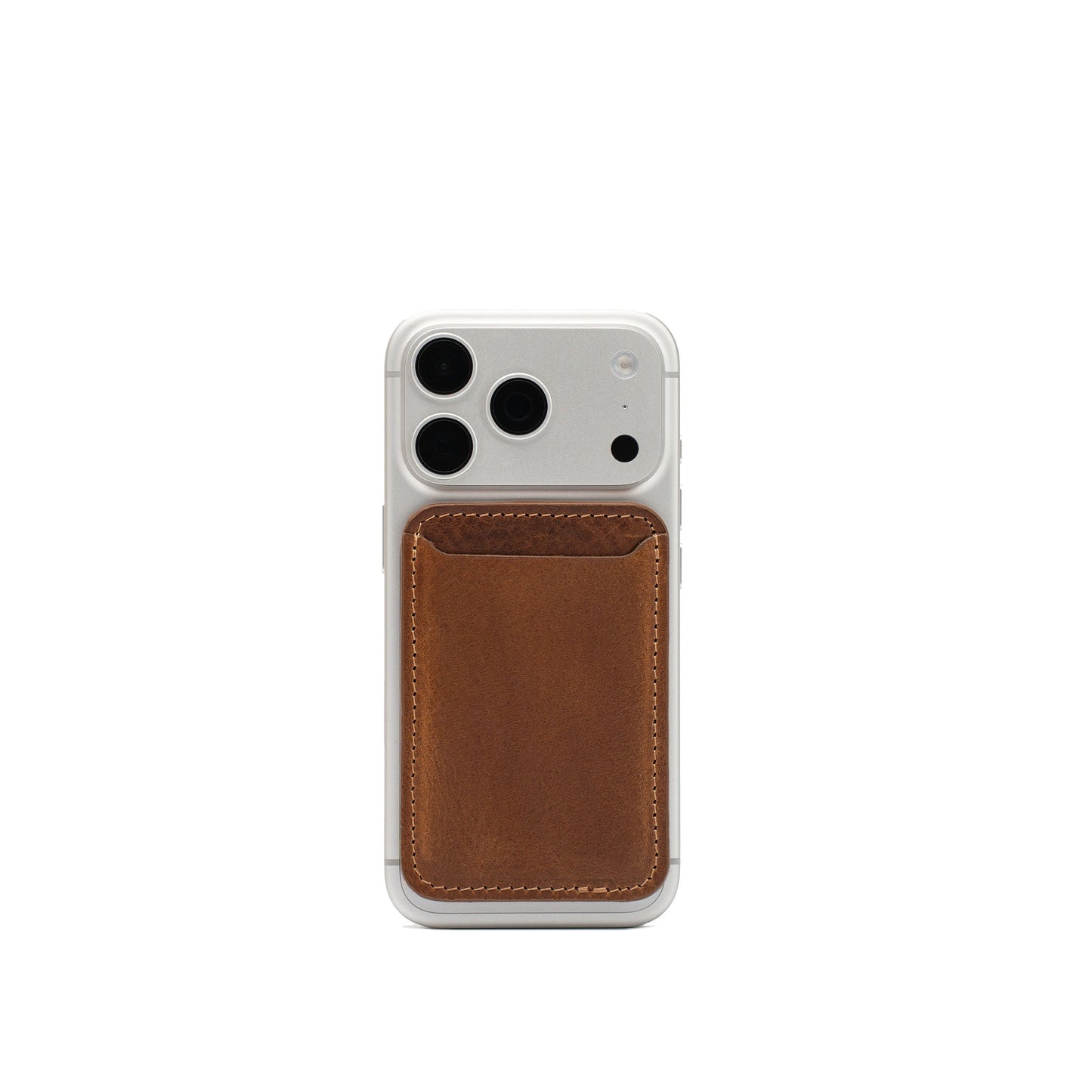 Brown full-grain leather MagSafe wallet attached to the back of a white iPhone
