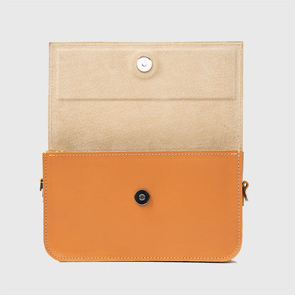 Close-up of light-orange leather purse showing structured design and stitching.