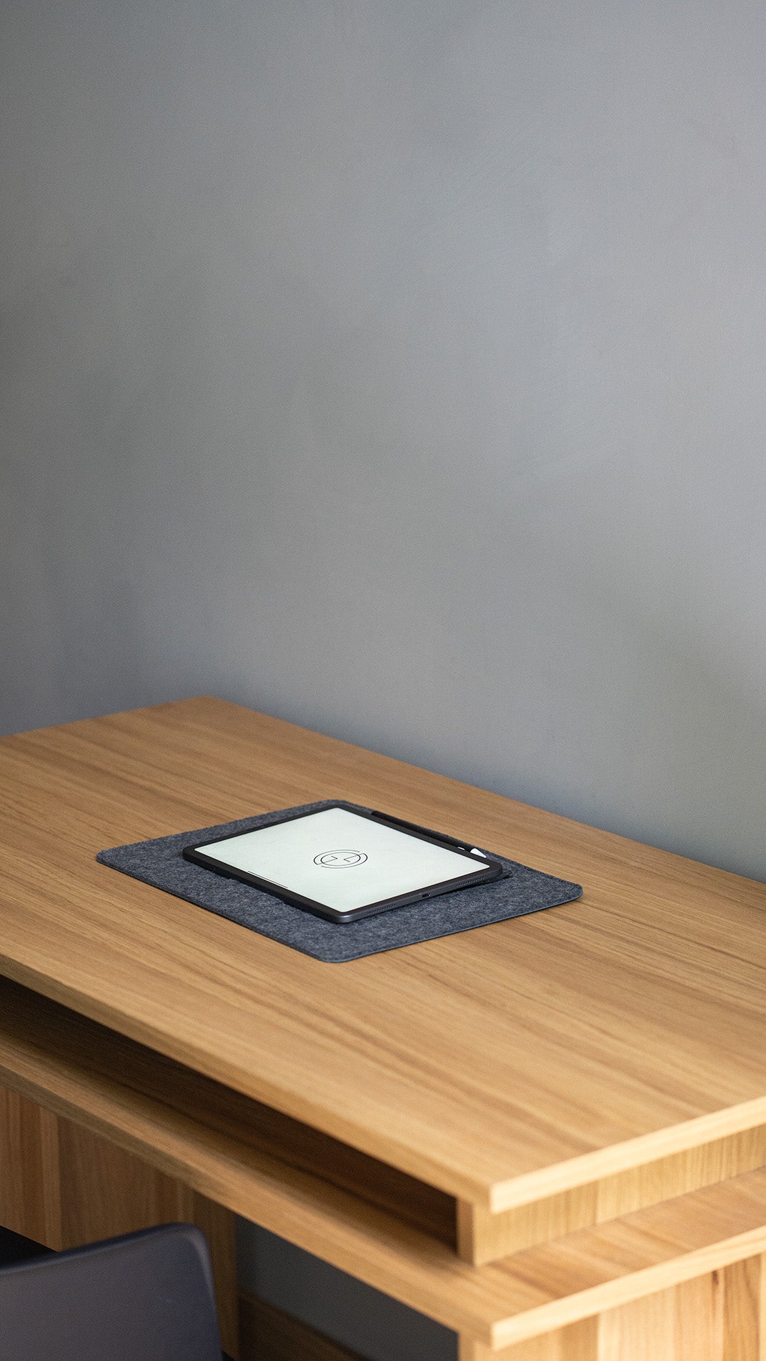 Grey wool felt desk pad with tablet on wooden desk