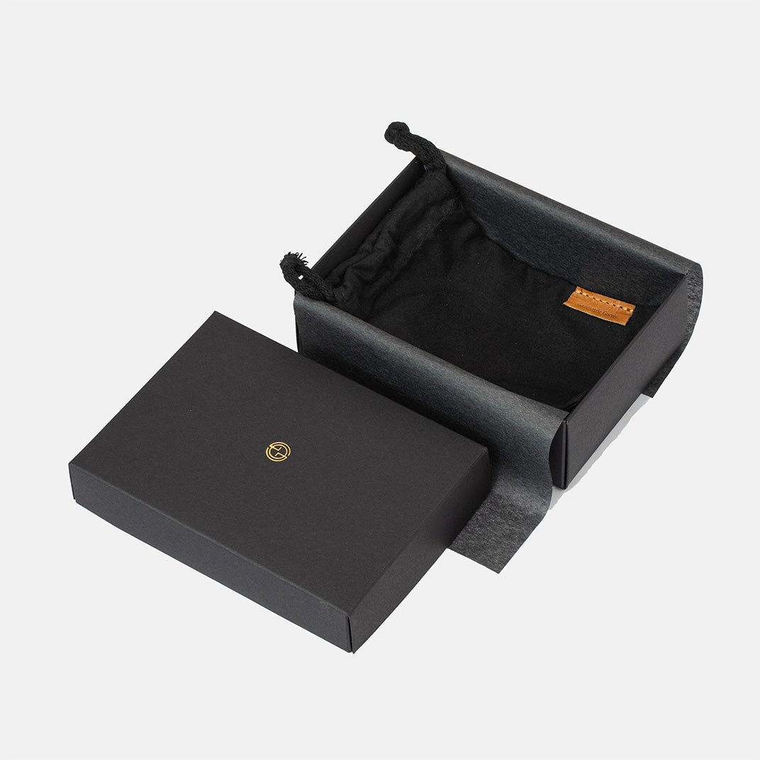 Geometric Goods gift packaging: black box with drawstring pouch and tissue paper, studio photo