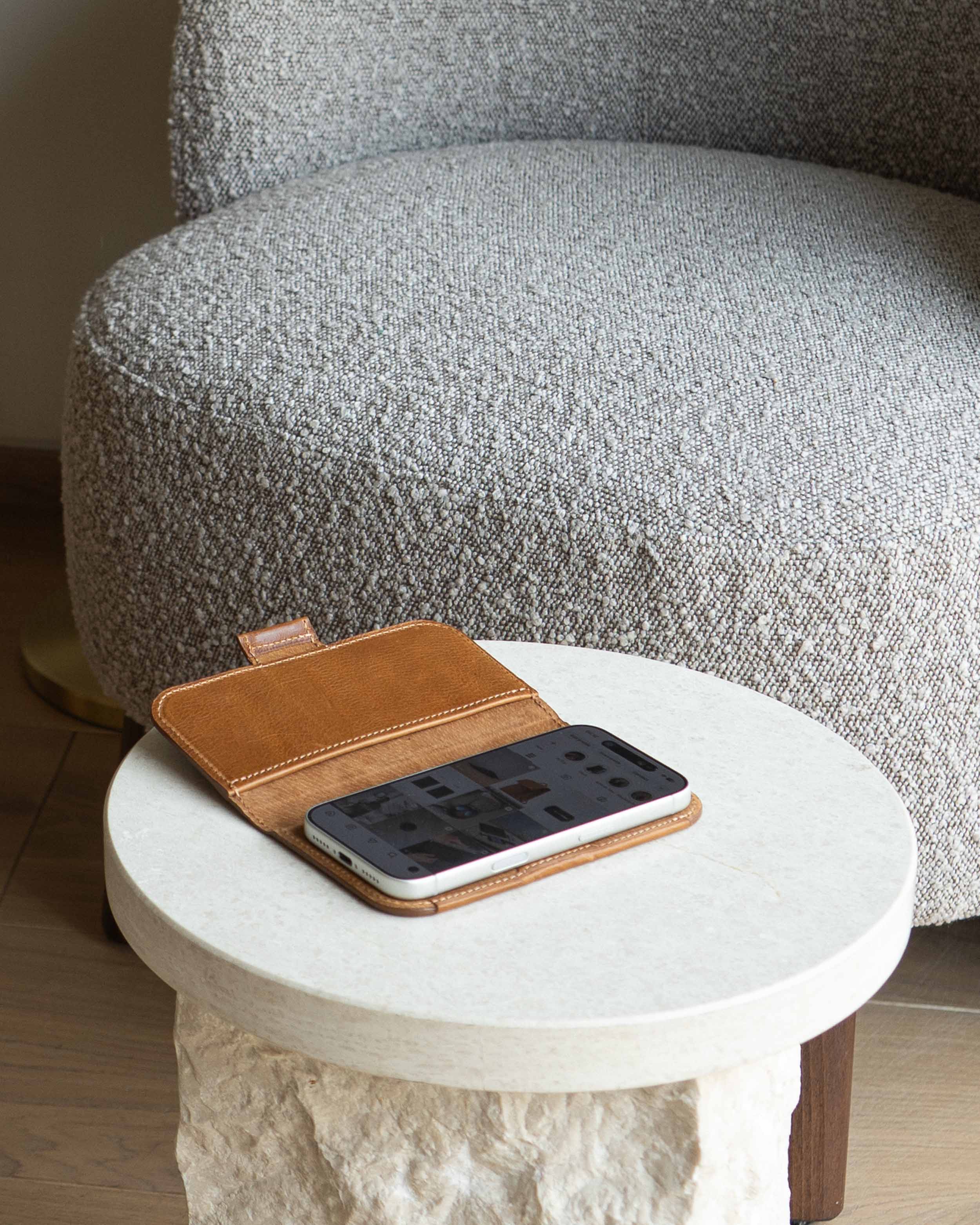 Open brown leather folio wallet case with iPhone 17 and MagSafe on a marble side table