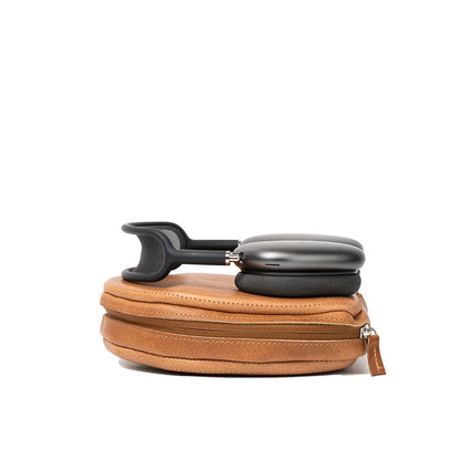 Closed brown leather AirPods Max case by Geometric Goods with headphones resting on top, showing zipper and structured form