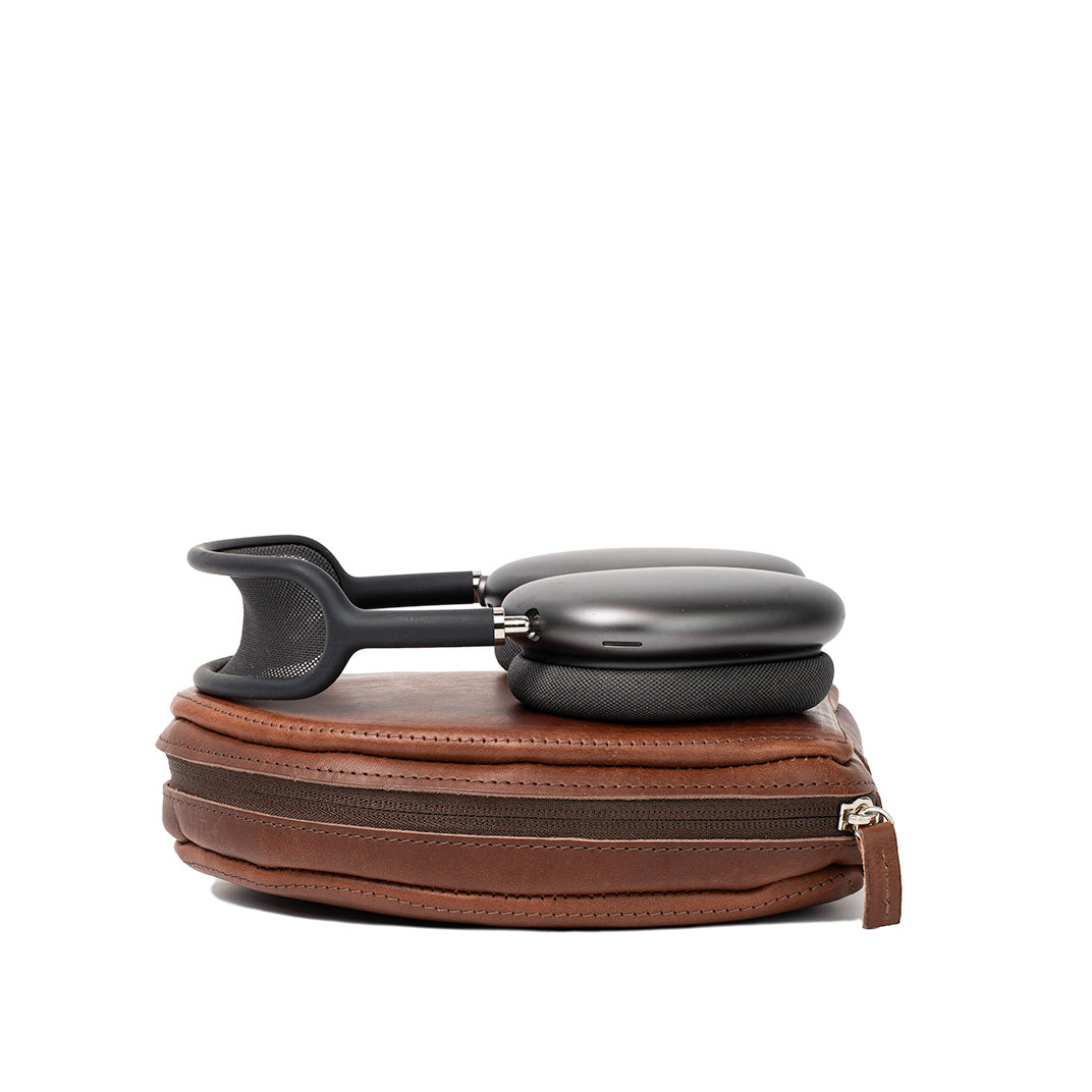 Closed AirPods Max case in Mahogany leather by Geometric Goods with headphones resting on top, showing zipper and structured profile