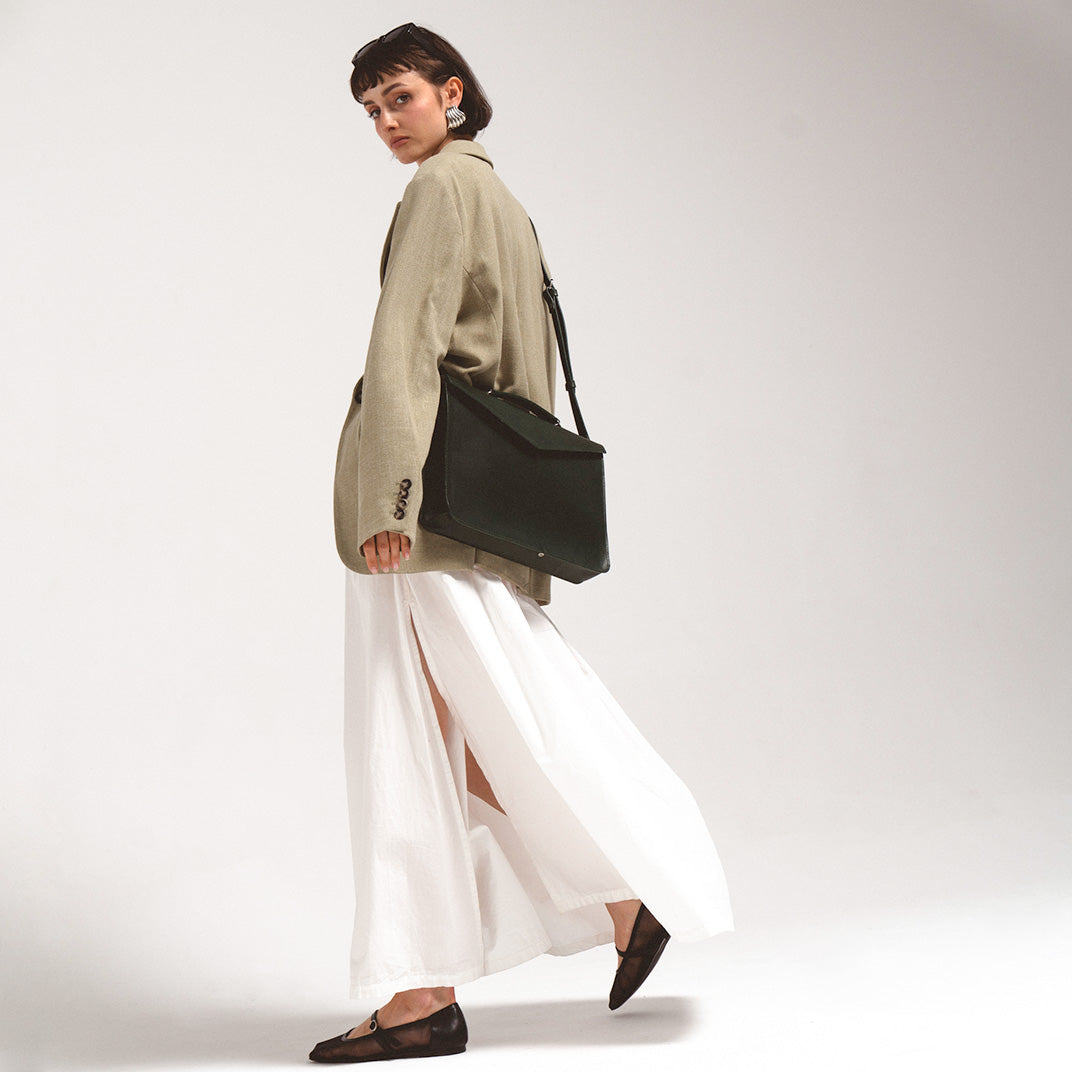 Leather Briefcase worn crossbody by a woman in a stylish outfit, showcasing the bag's practical and elegant design. Forest Green color made by Geometric Good