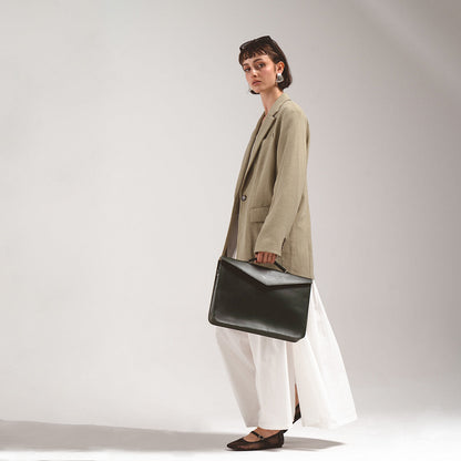 Leather Briefcase (Forest Green) by Geometric Goods, held by a woman in a beige blazer and white skirt, highlighting the sleek and professional design