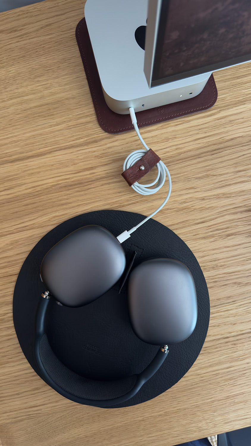 Leather cord organizer managing Apple charging cable on desk setup