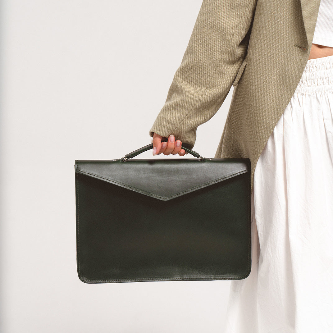 Leather laptop bag for women in forest green, carried by a woman in a beige blazer and white skirt, showcasing a stylish and professional design