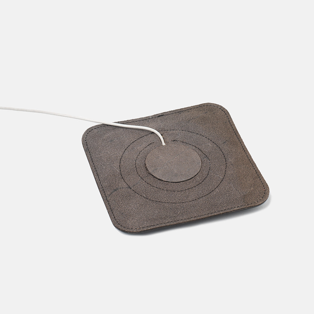 Underside view of leather MagSafe charging mat showing suede texture and cable channel