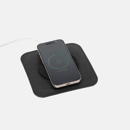 Black Italian leather MagSafe charging mat with iPhone placed on top, minimalist wireless charger pad