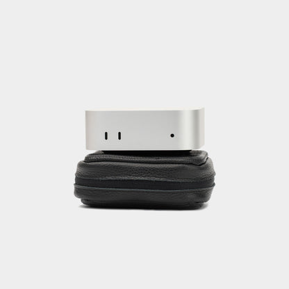 Apple Mac Mini resting on a closed black leather case to show size and structured profile