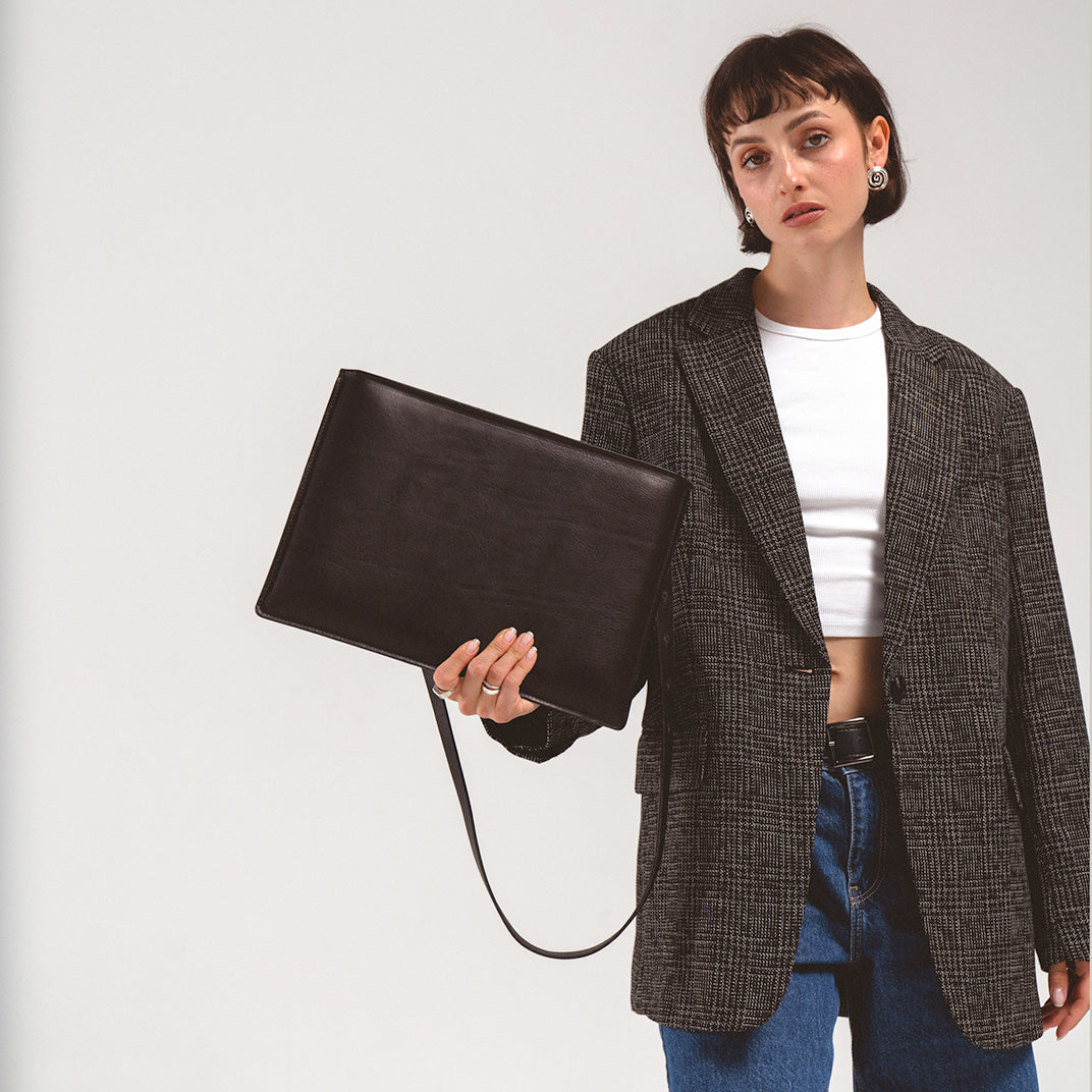 MacBook sleeve - Slim leather sleeve for MacBook held by a woman in a black blazer and white shirt