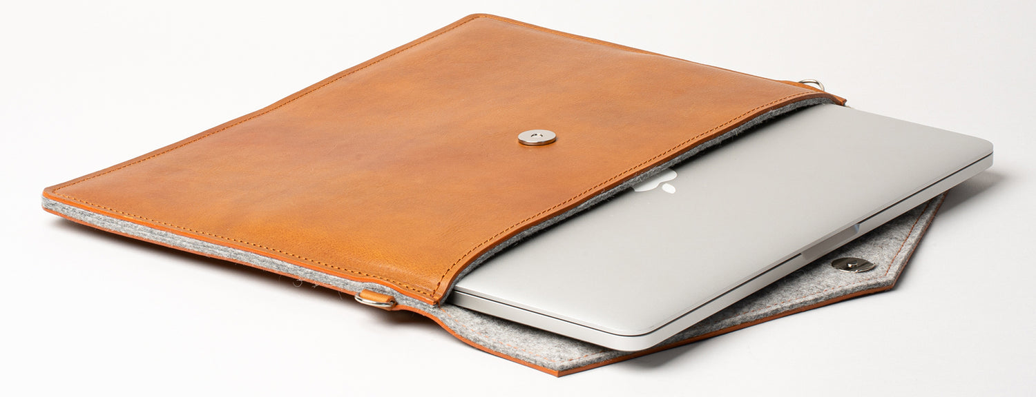 Brown leather laptop sleeve with a snap-button flap, partially open to show a slim laptop inside and a soft felt-lined interior.