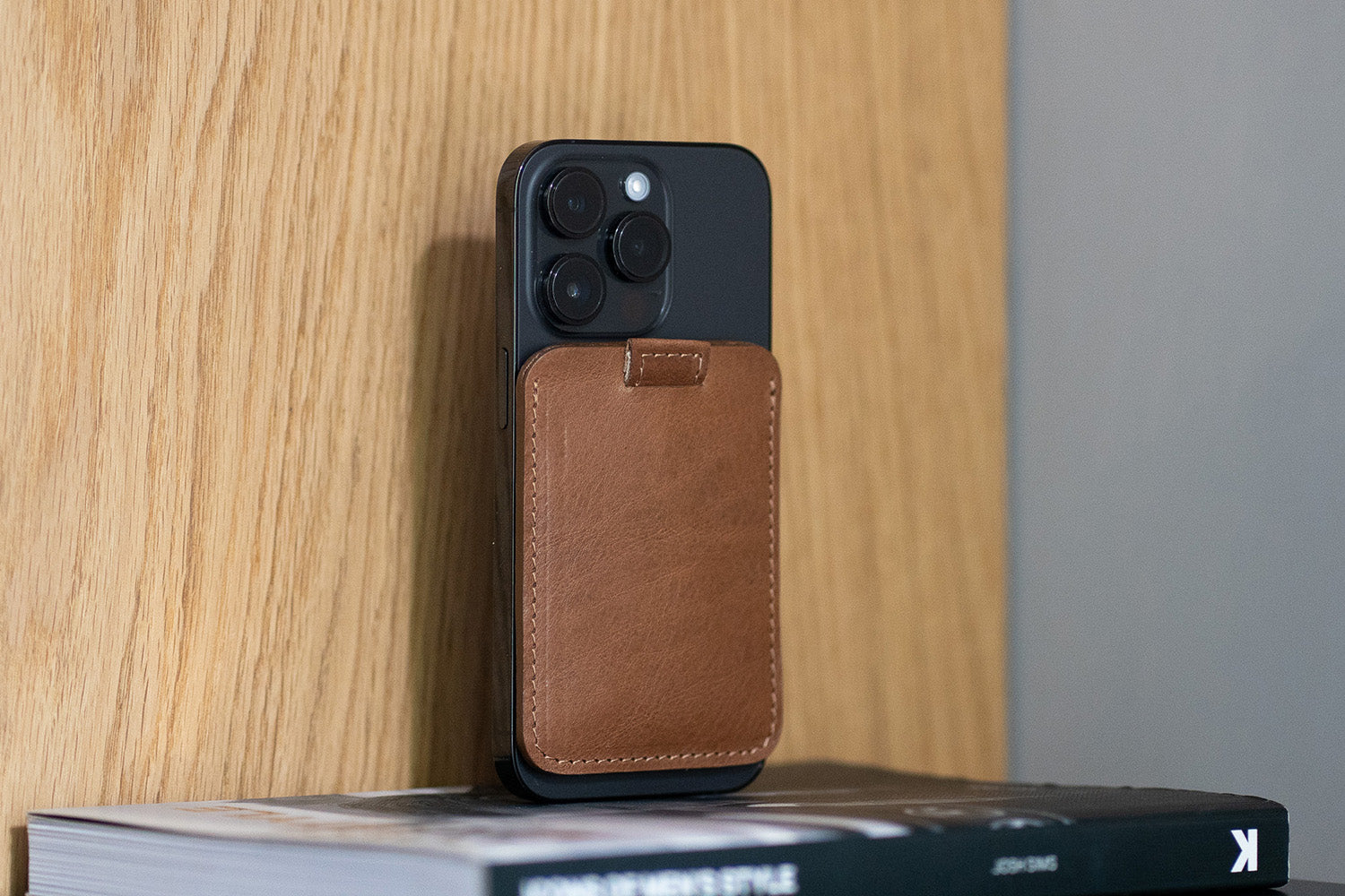 Leather card wallet attached to the back of a smartphone, holding multiple cards.