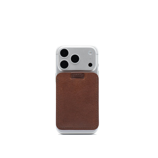 Mahogany full-grain leather MagSafe wallet attached to the back of a silver iPhone