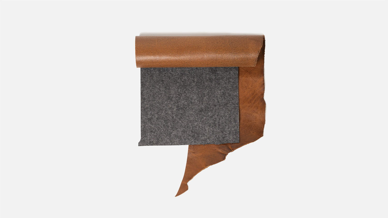 Rolled strip of tan vegetable-tanned leather draped over a rectangular sheet of dark gray merino wool felt on a white background (flat-lay).