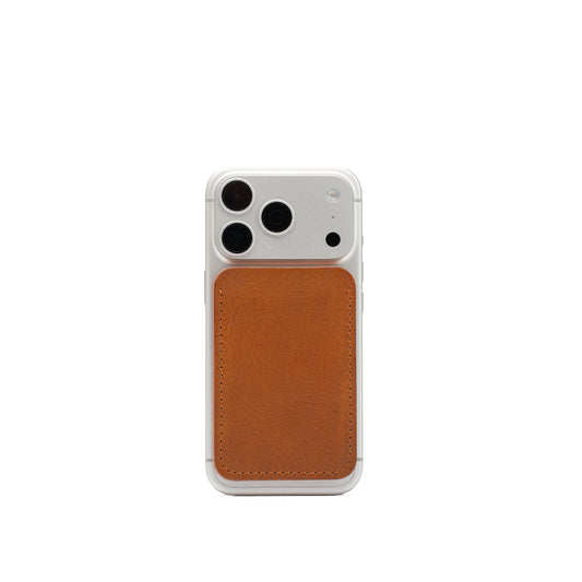 tan minimalist leather MagSafe wallet attached to the back of a white iPhone